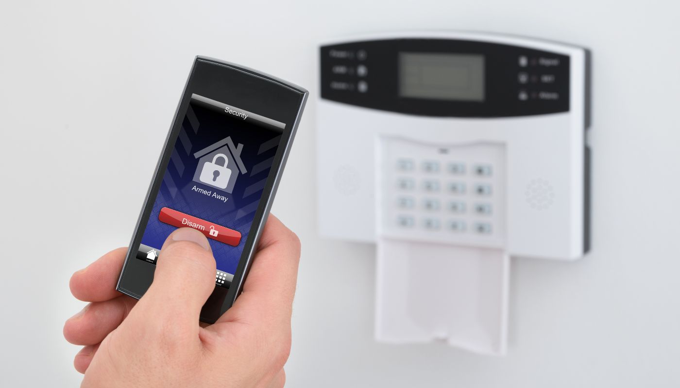 There is an alarm on the wall with a phone that grants access and a padlock and house on it.