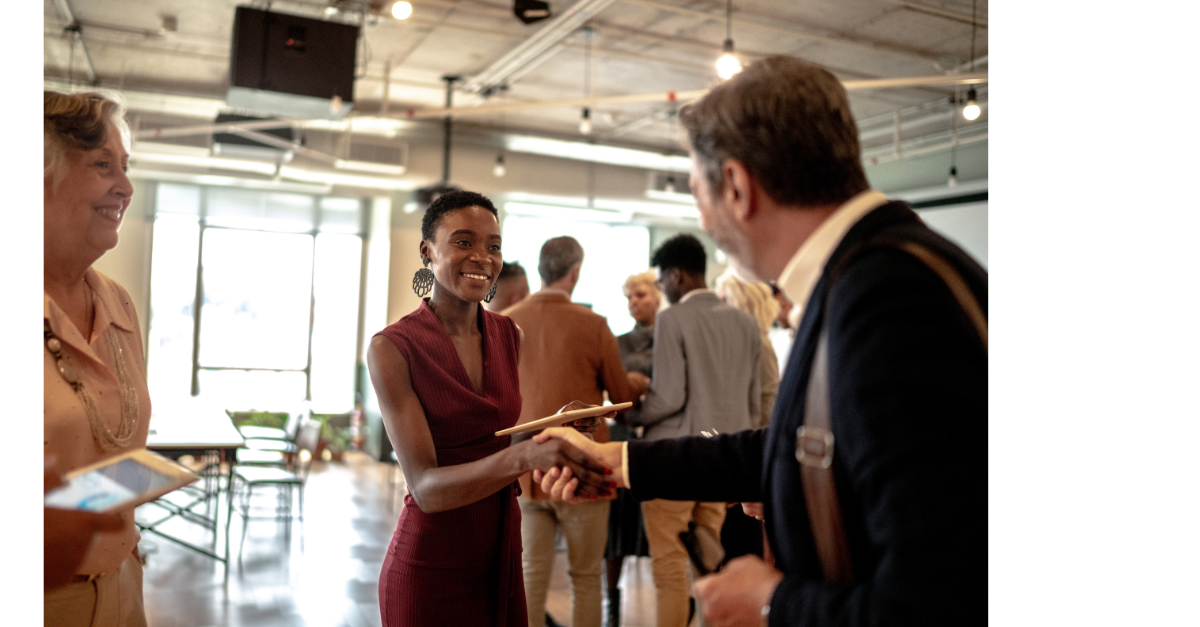 Two people having a handshake at a networking event in fancy clothes.