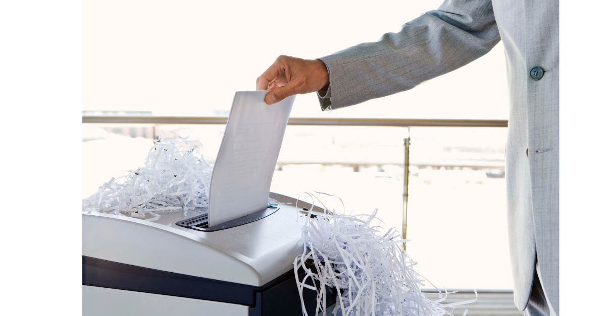 A man in a suit is shredding paper in a machine.