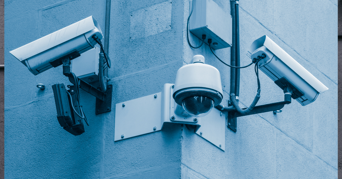 There are three cameras on a wall outside looking in all different directions.