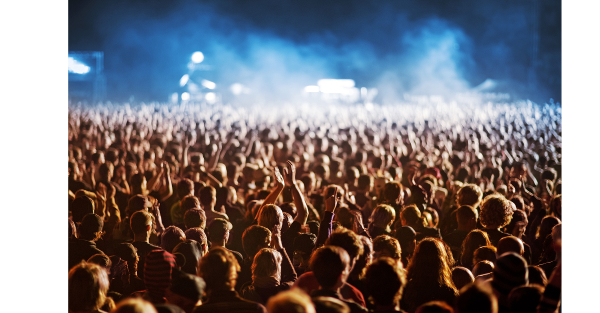 A massive crowd of people at an event with blue smoke in the air.