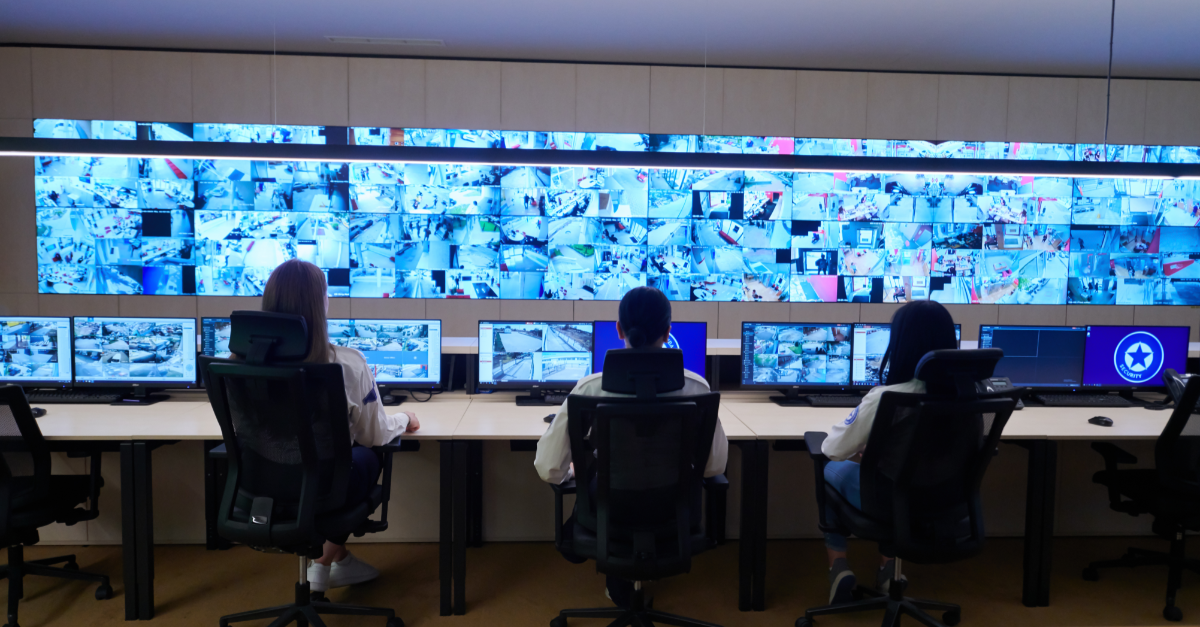A team of people at their desk in front of a large screen showing CCTV footage in an operations room.