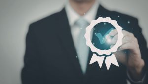 A business man has a badge with a tick in it showing a well done.