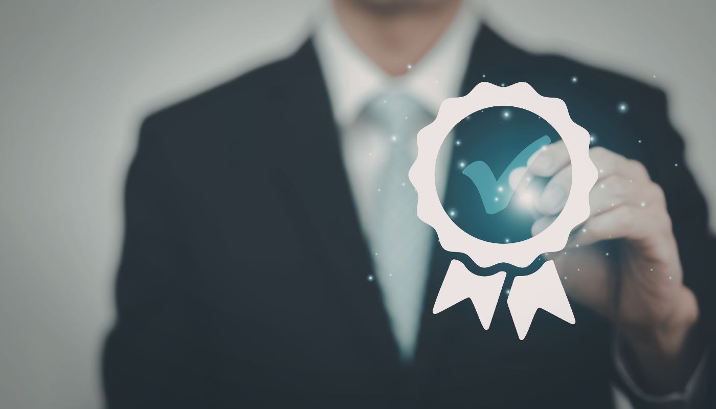 A business man has a badge with a tick in it showing a well done.