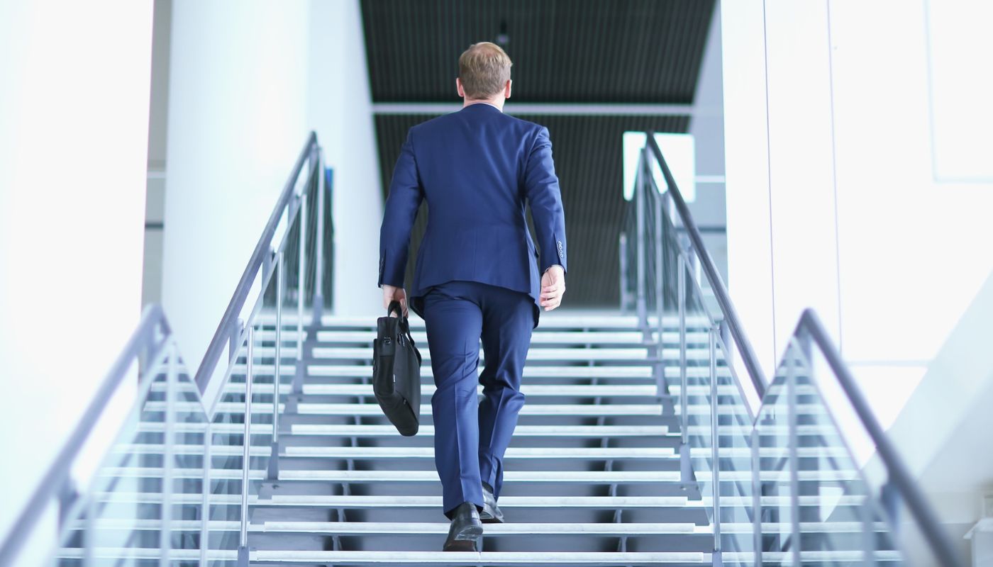 A business man walking upstairs holding a briefcase.
