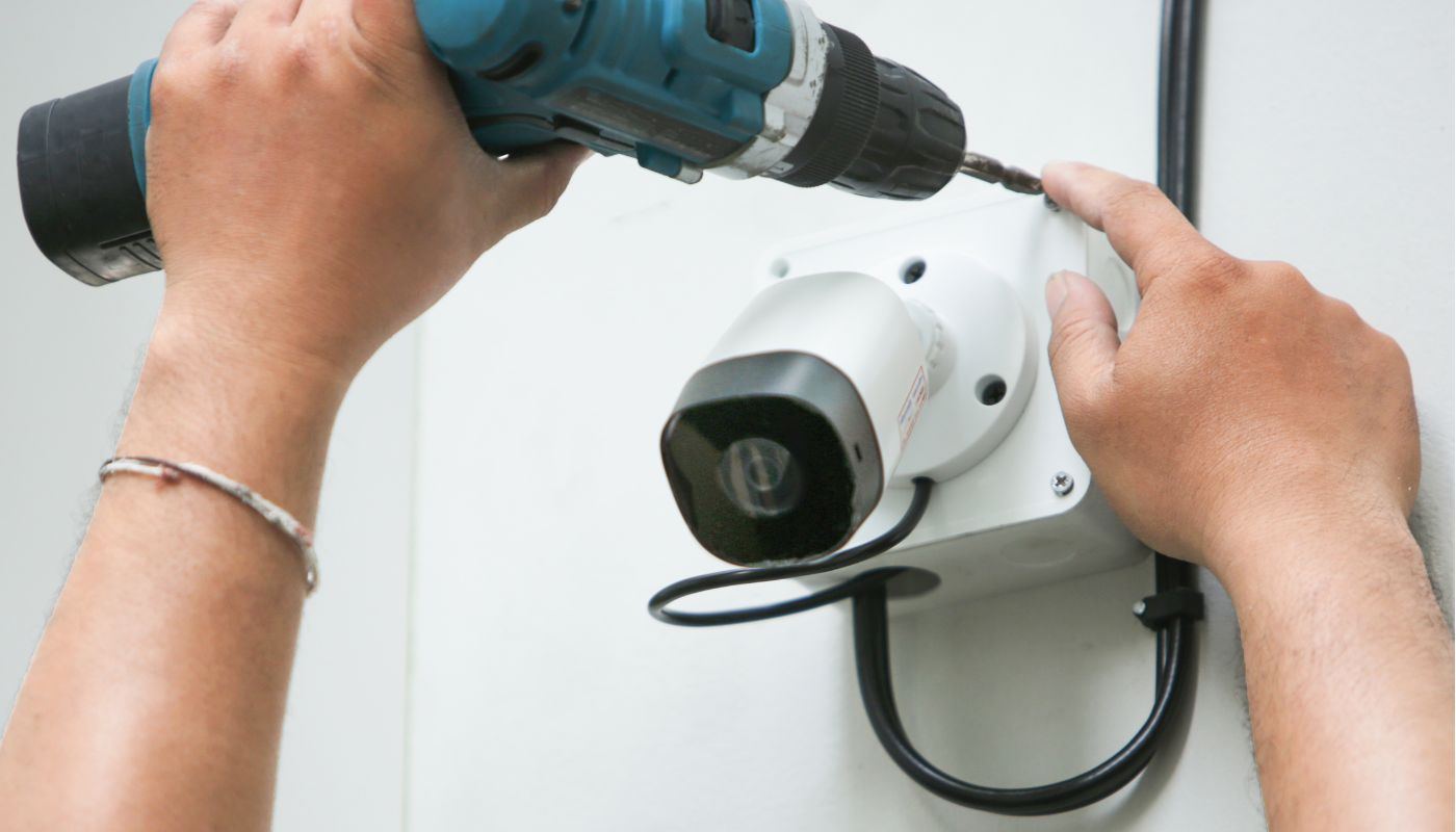 Someone is drilling a CCTV camera to a wall.