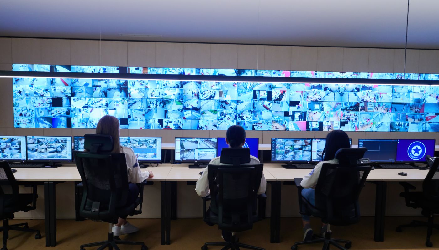 A team of people at their desk in front of a large screen showing CCTV footage in an operations room.