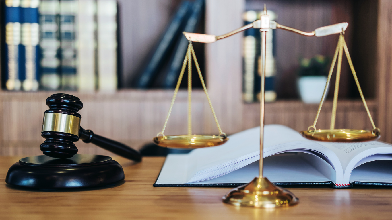 A gavel on a block with weight scales and a book.