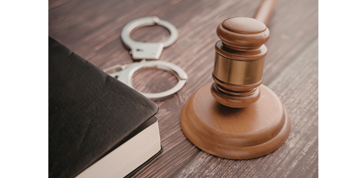 A gavel on a block with handcuffs and a book.