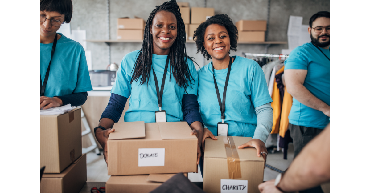 There are a group of voluntary workers holding boxes and wearing blue polo shirts with lanyards on smiling.