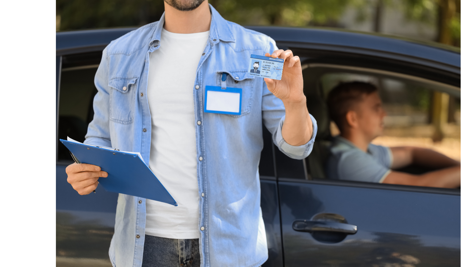 A man is holding a driving licence up in front of a car and holding a clipboard.
