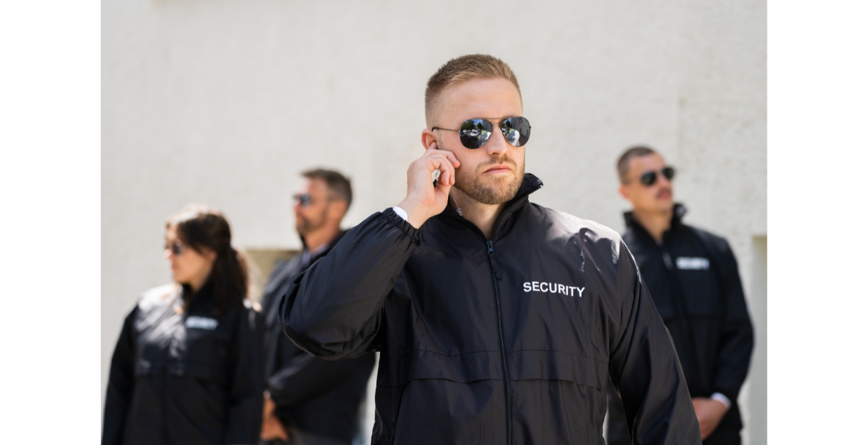 There are a team of security guards and one is touching their earpiece.