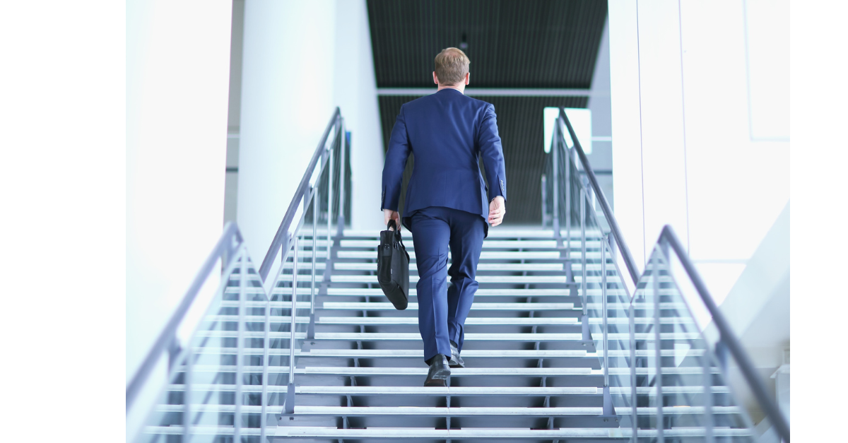 A business man walking upstairs holding a briefcase.