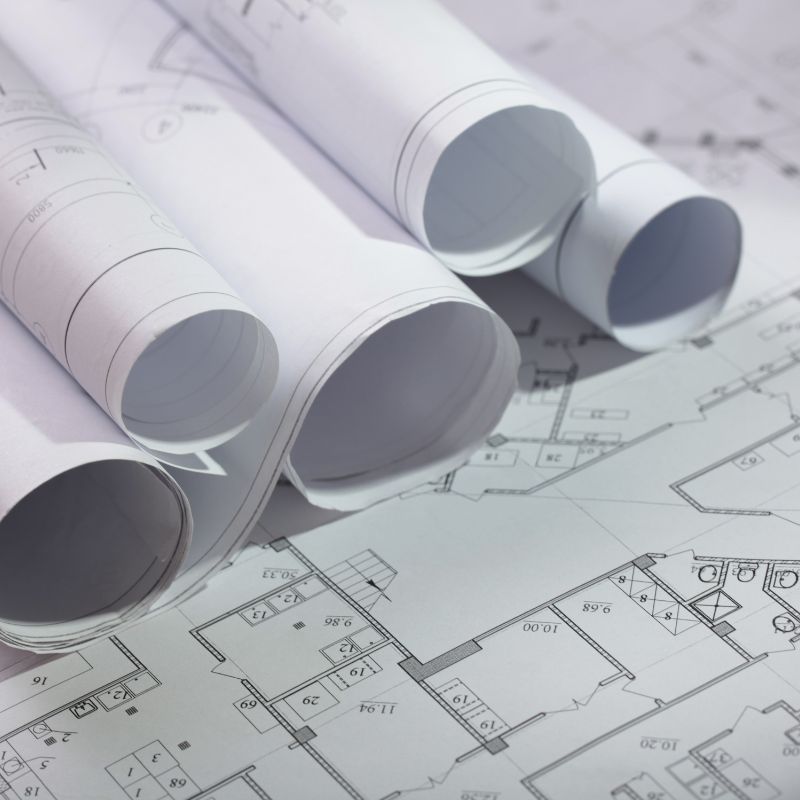 Rolls of floor plans stacked on an open floor plan.