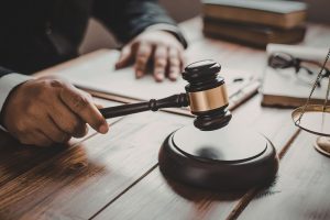 A dark wooden gavel held by a judge about to hit a wooden block for court order.