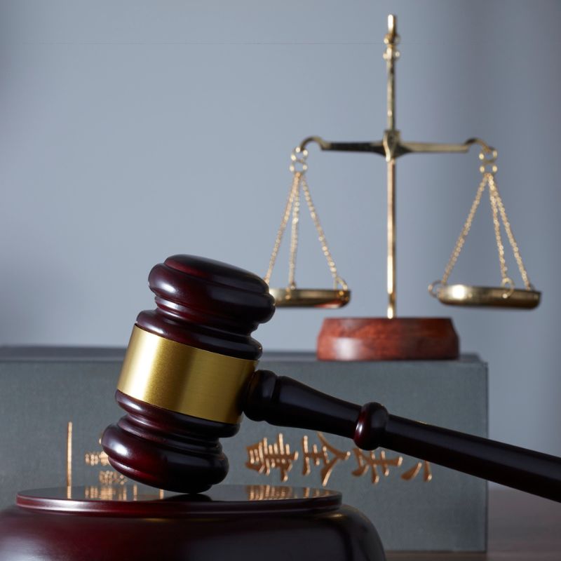 A gavel on a wooden block with weight scales behind it.