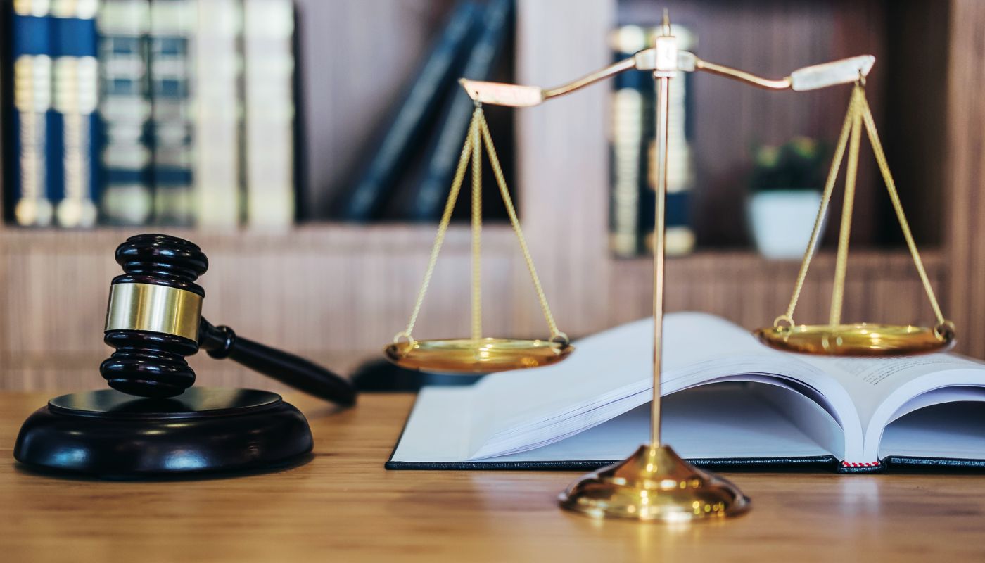 A gavel on a block with weight scales and a book.