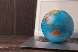 A globe is on top of an open laptop.