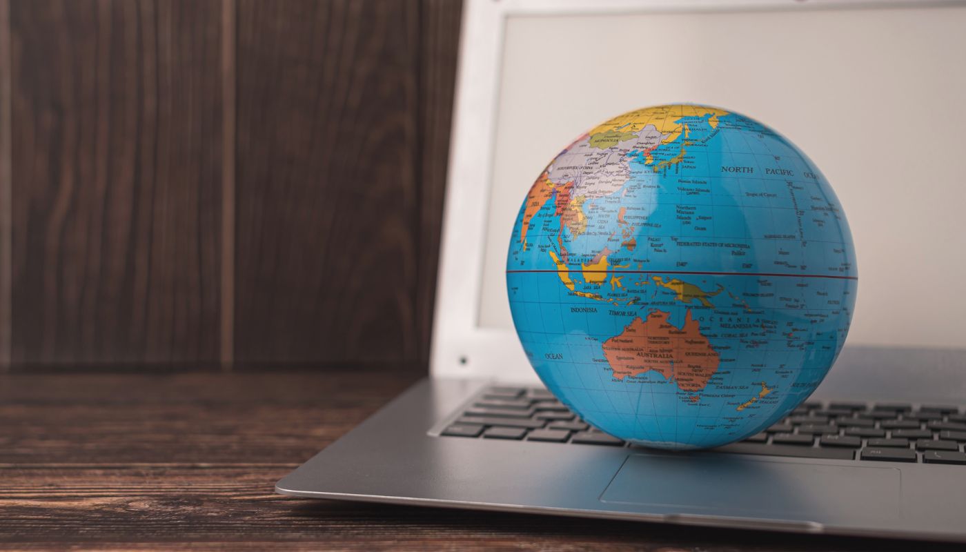A globe is on top of an open laptop.