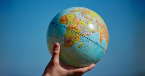 A hand is holding a globe in the air.