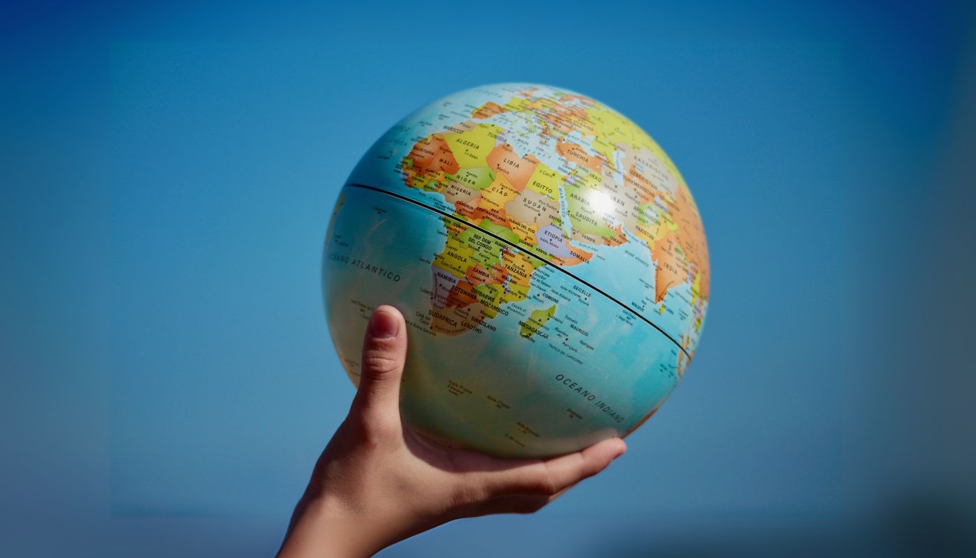 A hand is holding a globe in the air.