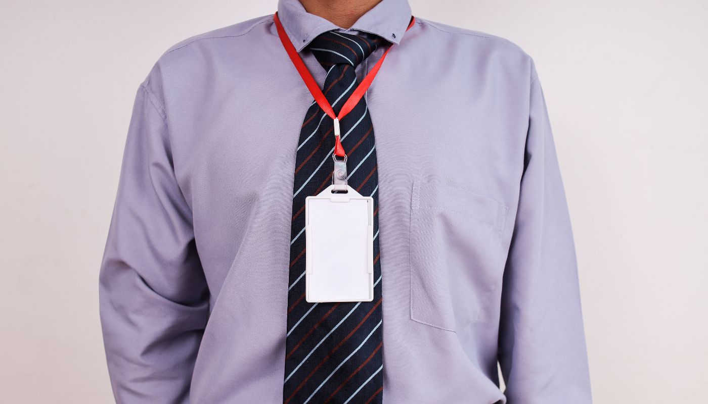 A close up of a business man's outfit with a red lanyard and a ID card on it.