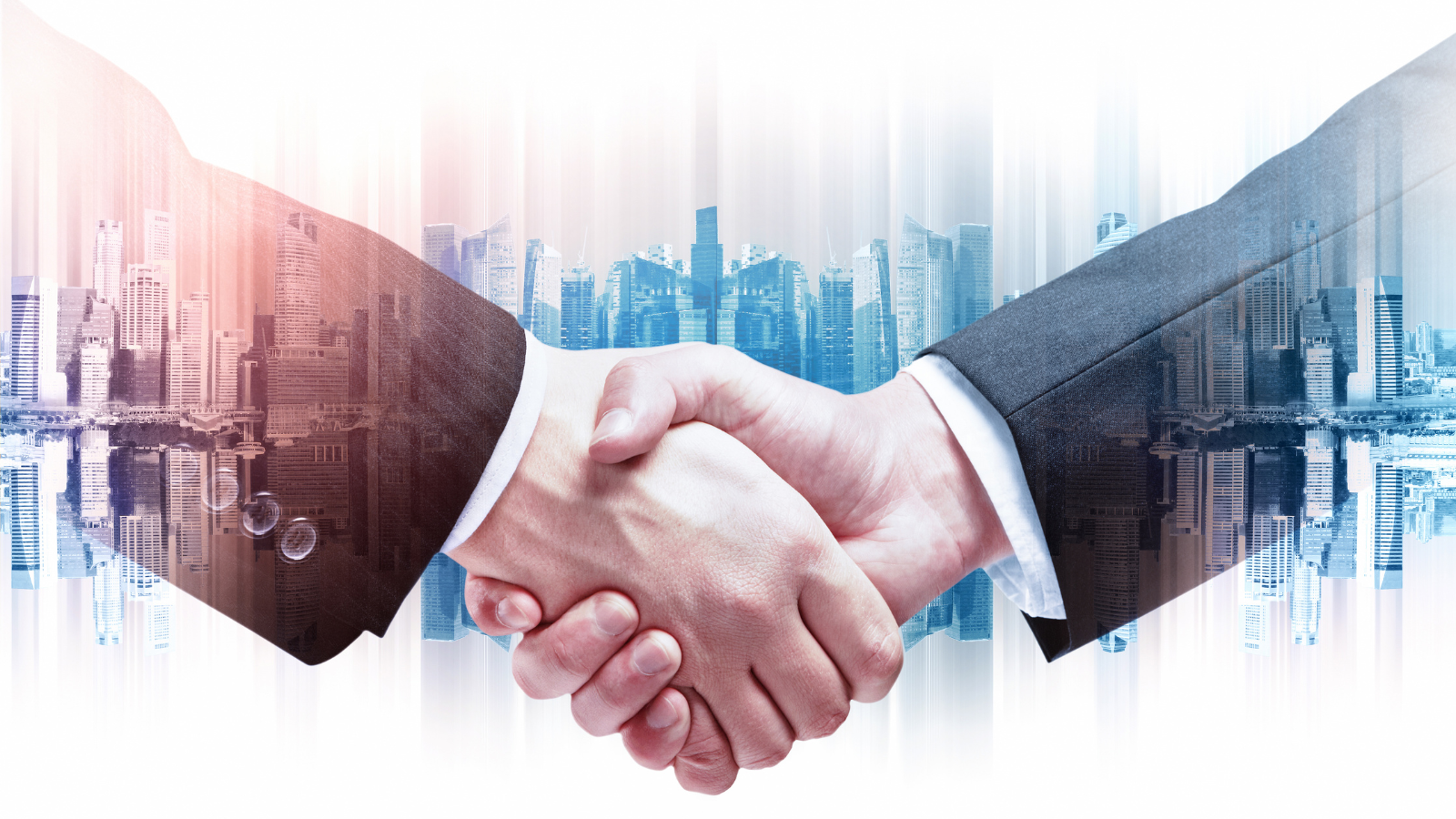 Two business men in suits are shaking hands with an illusion of a skyline with buildings in a city.
