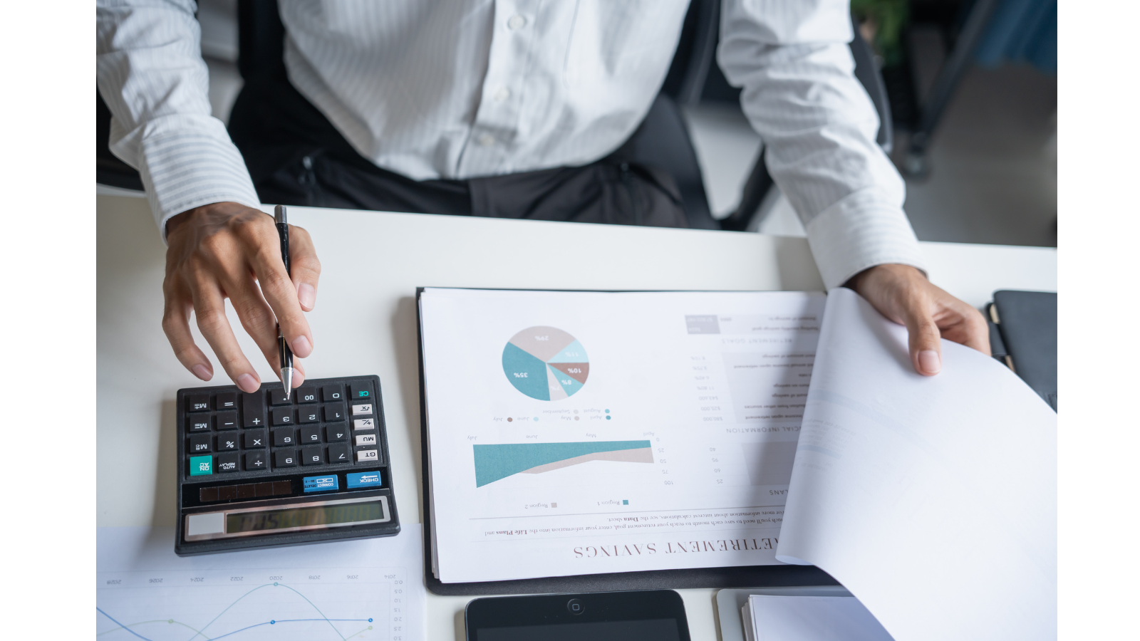 A business man is reviewing documents and clicking buttons on a calculator with a pen in hand.
