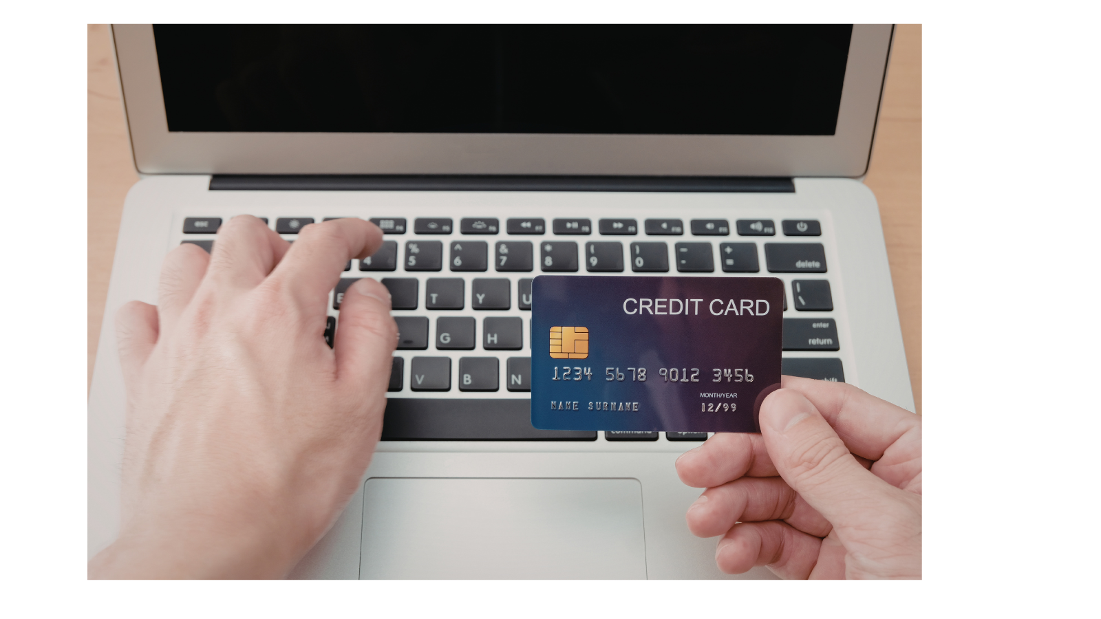 Someone is typing on a laptop reading their credit card details.