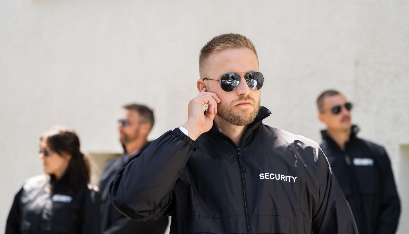 There are a team of security guards and one is touching their earpiece.