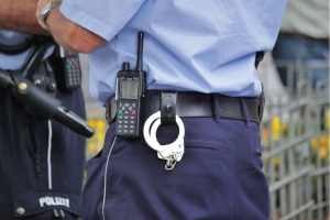 A close up of two guard's belts with handcuffs and a walkie talkies hanging off of them.