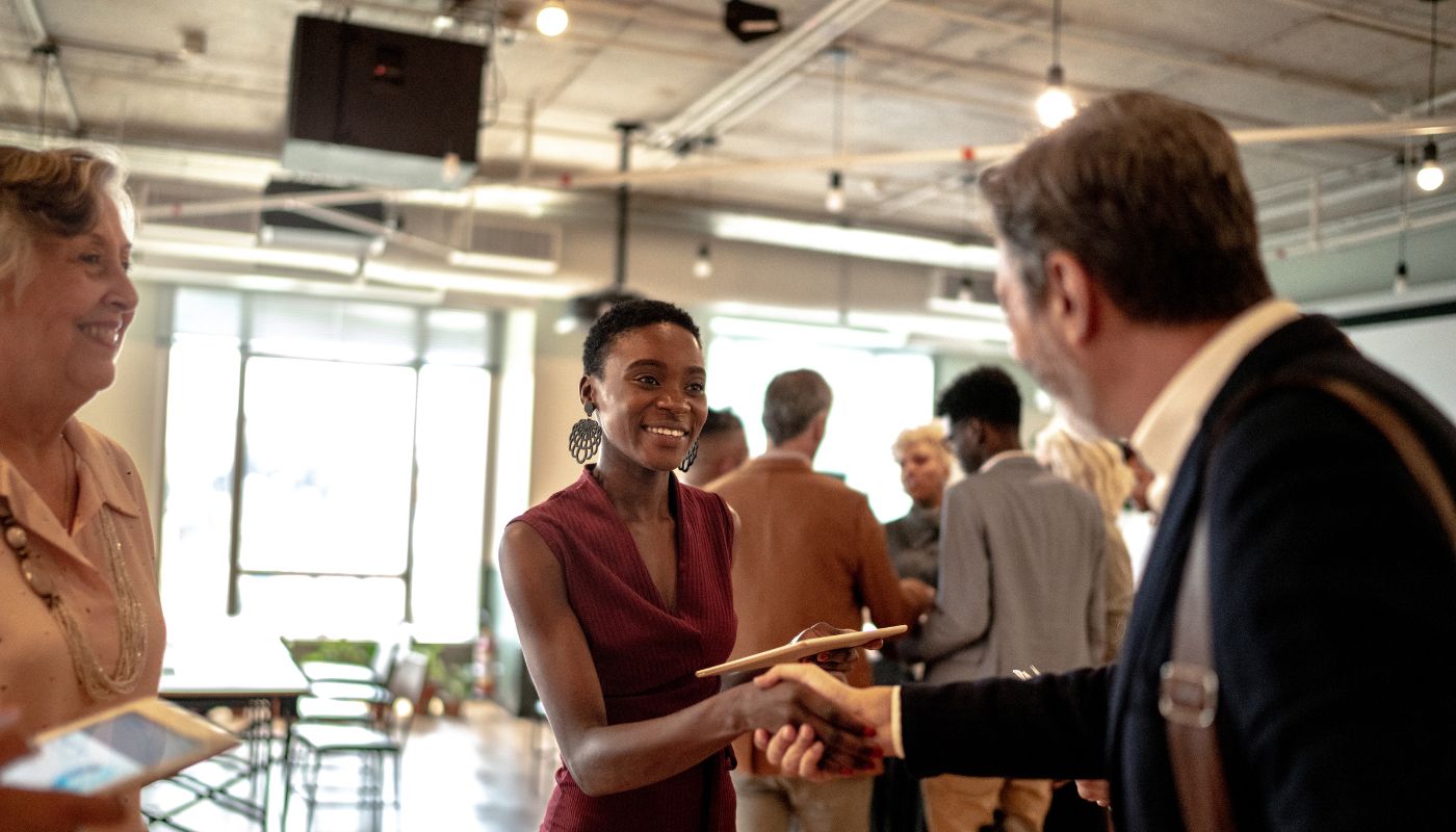 Two people having a handshake at a networking event in fancy clothes.