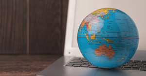 A globe is on top of an open laptop.