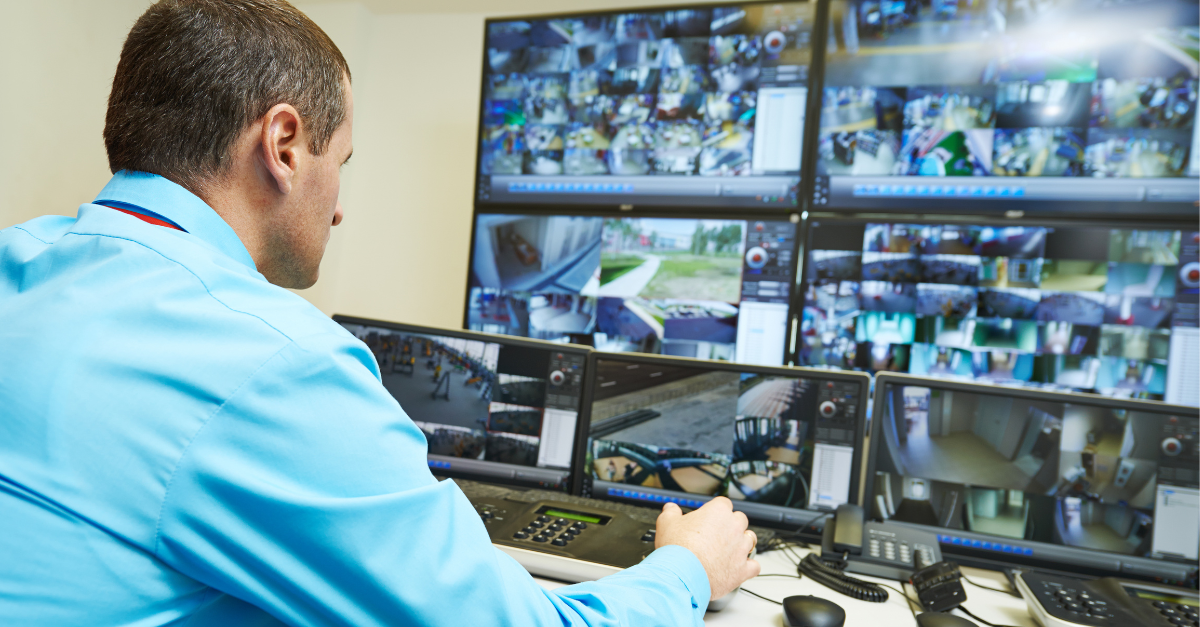 A man is in a control room operating the CCTV on the many screens.
