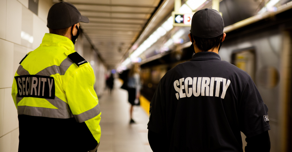 Two security men are walking through an underground tube station.