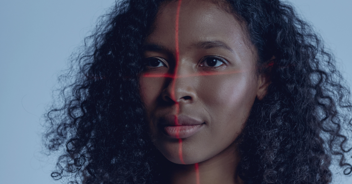 A close up of a women's face with a red line going down the middle and across the middle of her face to be digitally scanned.