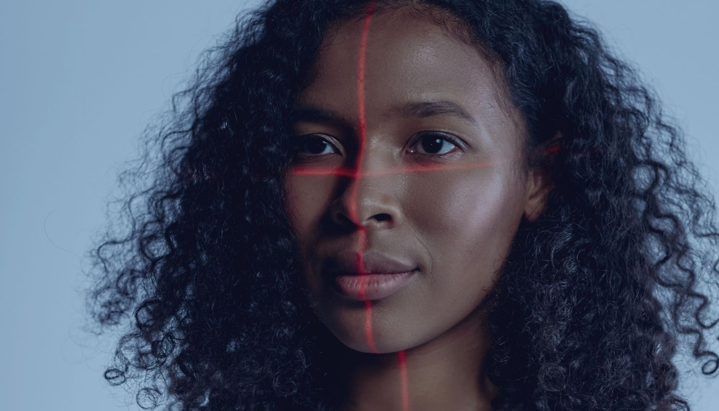 A close up of a women's face with a red line going down the middle and across the middle of her face to be digitally scanned.