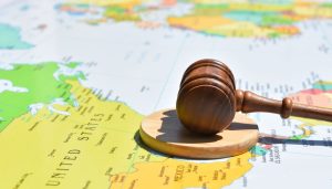 There is a world map with a gavel and block on top of it.