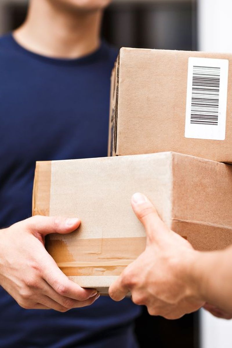 A person is delivering parcels to a client handing over boxes.