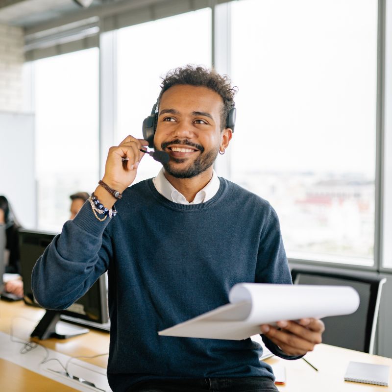 A man with a headset on and a piece of paper in hand.