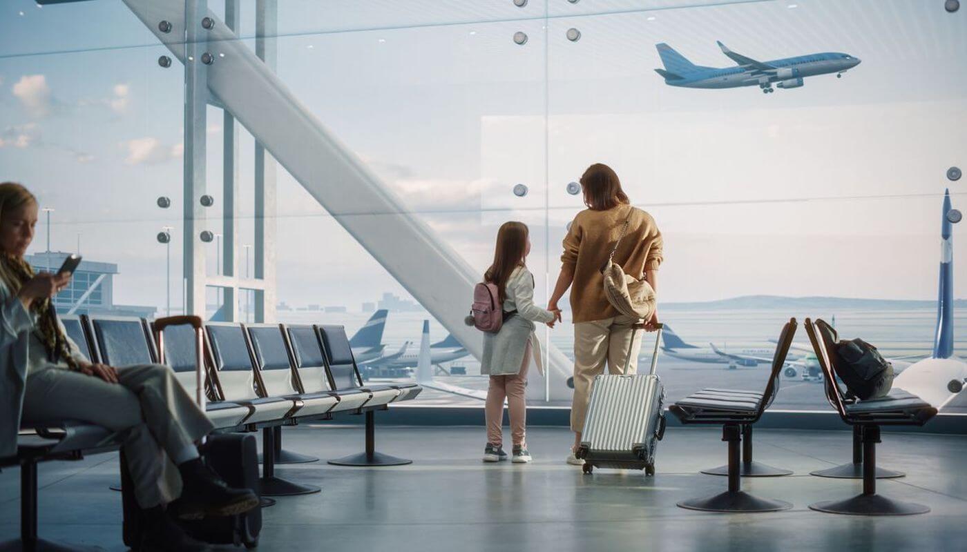 Passengers in airport terminal looking at a plane out the window.