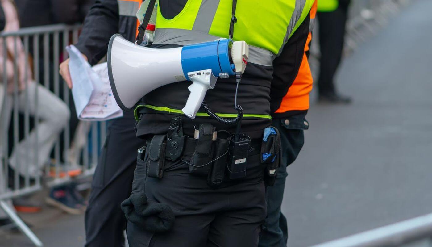 An event security guard wearing a hi-vis with a megaphone.