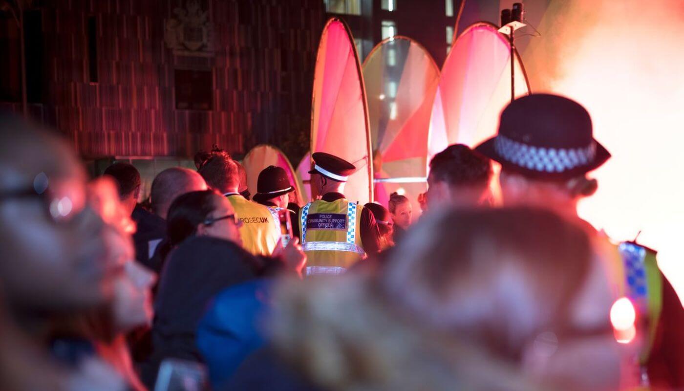 Police entering an event at night time with a crowd of people.